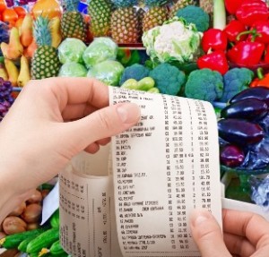 hand holds the check from supermarket against vegetables and fruit